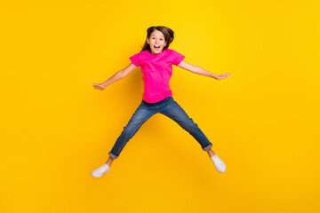 Fototapeta na wymiar Photo of crazy active cheerful girl jump open mouth wear pink t-shirt jeans sneakers isolated yellow color background