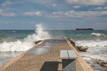 Jetty on a windy day. Cargo ship in the distance. Stock Image.
