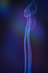 A vertical shot of smoke in colorfull backlight with a blue note