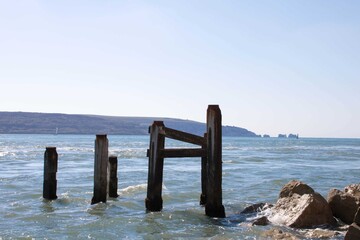 old wooden groynes in the sea with The Isle of Wight and The Needles in the background
