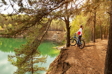 Girl resting on the shore of a mountain lake after walking a bike