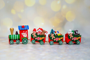 Christmas train on a background of golden lights bokeh. Santa Claus red wooden toy train with carriages. Selective focus. Merry Christmas and Happy New Year greeting card. space for text.