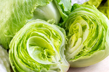 Fresh green iceberg lettuce salad leaves cut on light background on the table in the kitchen. - obrazy, fototapety, plakaty