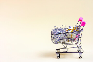 Trolley shopping cart with silver Xmas and Birthday boxes for gifts and presents on light...