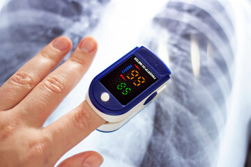 Woman hand with medical fingertip pulse oximeter tool for oxygen saturation check during covid...