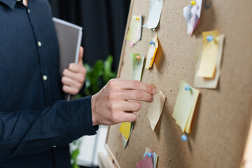 Cropped view of programmer pinning sticky notes on board
