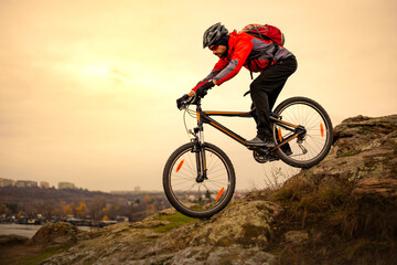 Naklejka na ściany i meble Cyclist Riding the Mountain Bike on the Rocky Trail at Cold Autumn Evening. Extreme Sport and Enduro Cycling Concept.
