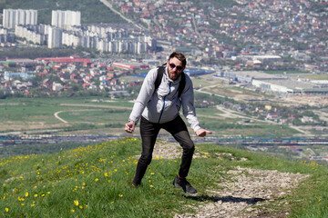 Fototapeta premium An emotional and happy guy is dancing on top of a mountain.