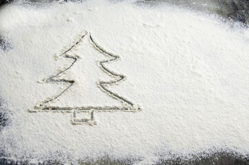 Drawn Christmas tree on flour scattered on the table. Silhouette of a Christmas tree made of flour on a dark concrete background of the kitchen table top. Holiday preparation concept, new year treats