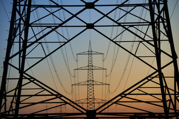Electricity pylon (Strommasten) also overhead line pylon. Construction forms windows. Winter evening at sunset.