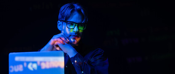 Young developer in eyeglasses near laptop with code reflection isolated on black, banner