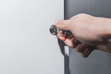 The hand of a human electrician opens or closes the electrical box with a metal key. Safe...