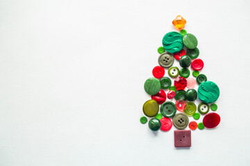 A Christmas tree made of buttons of green, red color. white background, copy space. Creative Christmas Concept