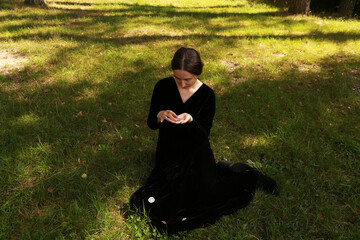 Woman in black dress holding medieval silver coin