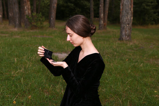 Young woman in black dress with old silver coins in her hands