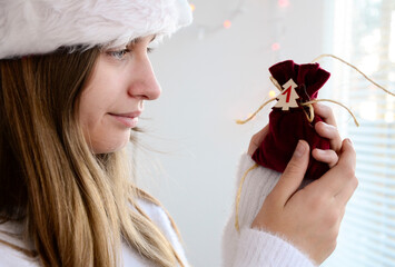 Child girl with long hair open small bags of gifts surprises advent calendar in her hands. Happy...