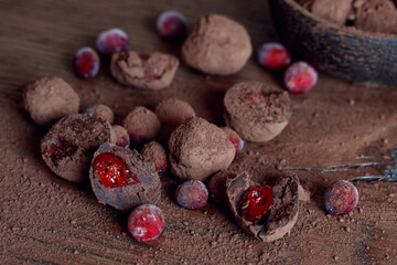 Homemade organic Cranberry truffles made of dark chocolate and frozen berries on solid oak table. Vegan truffles for healthy dessert..