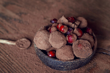 Homemade organic Cranberry truffles made of dark chocolate and frozen berries on solid oak table. Vegan truffles for healthy dessert..