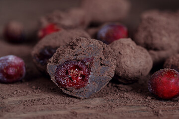 Homemade organic Cranberry truffles made of dark chocolate and frozen berries on solid oak table. Vegan truffles for healthy dessert..