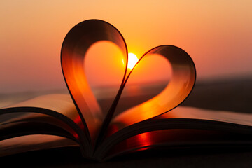 Heart from a book page against a beautiful sunset