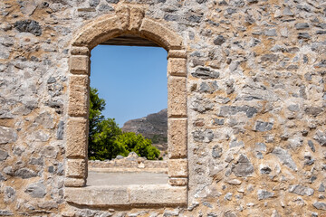 Fototapeta na wymiar Window frame with arch on a stone wall at Venetian Castle Fortezza at Chora Kythira island, Greece.