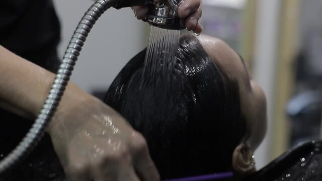 En un sal&oacute;n de belleza, una peluquer&iacute;a peinando el pelo mojado del cliente con masaje