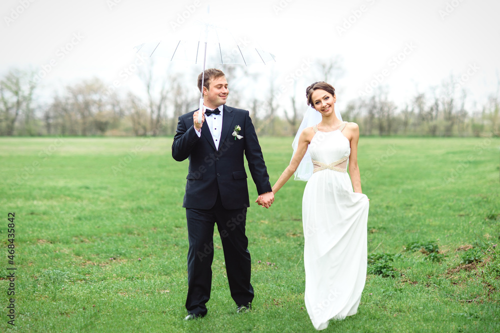 Wall mural bride and groom on a rainy wedding day walking