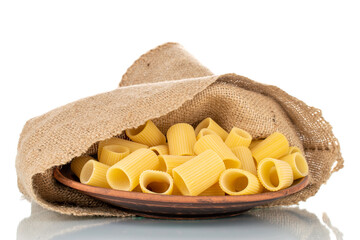 Uncooked organic cannelloni pasta with ceramic plate and jute bag, close-up, isolated on white.