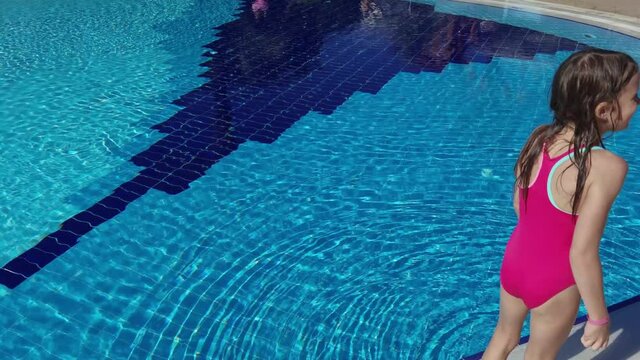 Little happy girl jumping in the pool and having fun