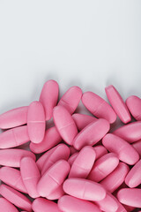 Pink pills with multivitamins on a white background.