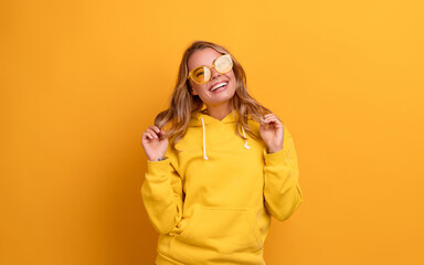 young pretty blonde woman cute face expression posing in yellow hoodie