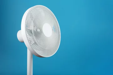 Foto op Plexiglas White modern electric fan for cooling the room on a blue background. © Alexander
