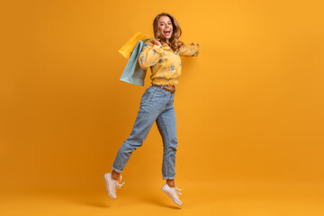 beautiful attractive smiling woman in yellow shirt and jeans with shopping bags