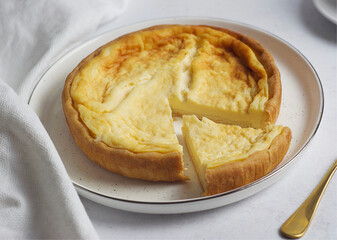 The curd cake is in a plate on the table. Nearby lies a white towel