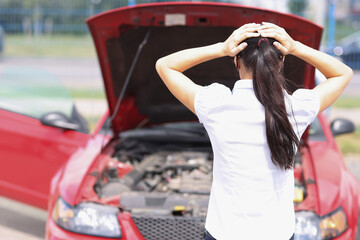 Plakat Sad woman holding her head near wrecked car