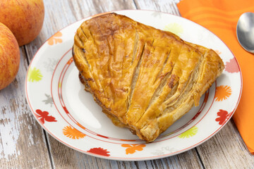 chausson aux pommes et deux pommes fraîches sur une table en bois