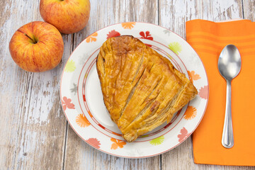 chausson aux pommes et deux pommes fraîches sur une table en bois