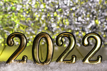 Gold numbers 2022 on snow with yellow backlight. New year backdrop with 2022 year