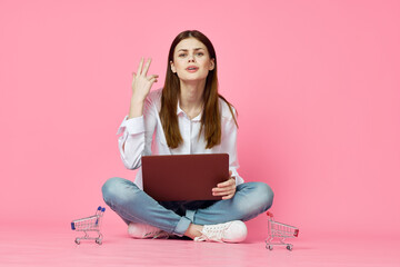 woman with laptop sitting on floor technology internet shopping pink background