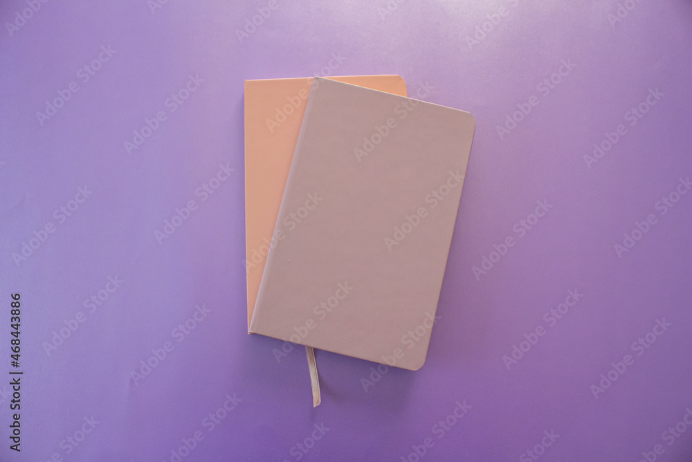 Poster top view of two notebook isolated on purple background.