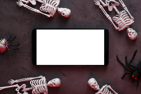 Decorative skeletons lie near the smartphone on a dark background.