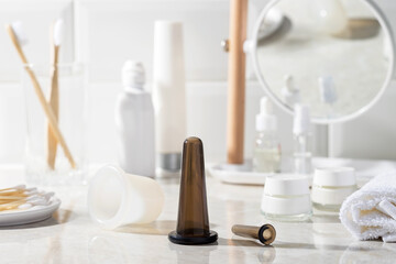 Fototapeta na wymiar Vacuum jar for massage in the bathroom. Mirror, massage oil, towel, cream, cotton swabs in the background.