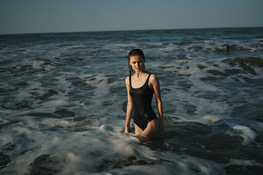 Cheerful woman black swimsuit ocean nature summer tan