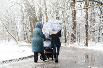 Woman with a baby stroller walking in winter park
