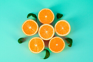 Juicy oranges laid out in the shape of a flower on a blue background.