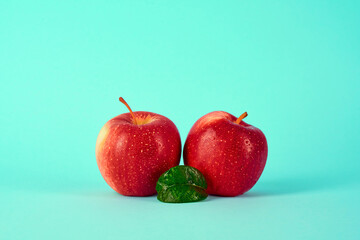 Apples with leaves on a blue background. The design of the advertising poster of an apple in the shape of eyes and a leaf in the middle in the shape of a nose.