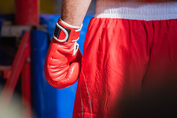 boxer in the corner of the ring in red shorts and gloves is large