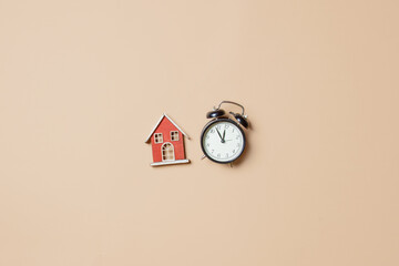 Little toy house and alarm clock on stark white background.