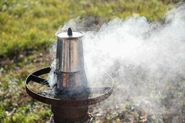 Making coffee in the garden in a geyser coffee maker on a wood-burning stove. A beautiful autumn day.
