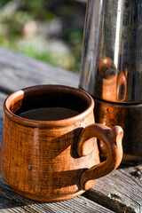Ceramic cup with coffee outside in the garden prepared in a geyser coffee maker.